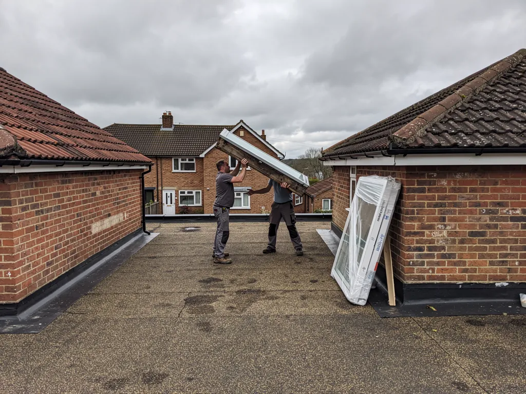 Fitters lifting an old rooflight off its kerb